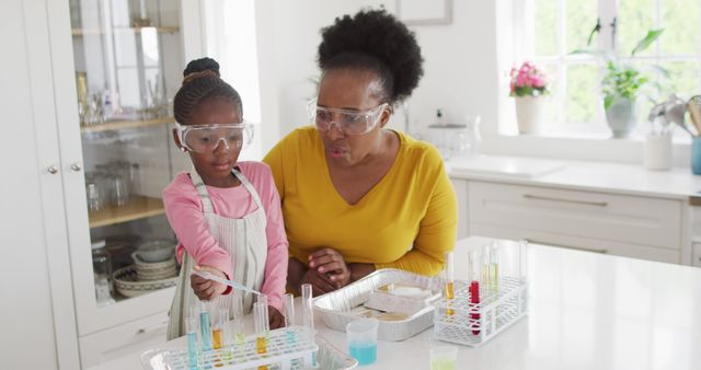 African American mother and daughter conducting science experiments at home. They are wearing safety goggles and using various laboratory equipment with colorful liquids. This can be used for educational materials, homeschooling resources, family bonding advertisements, and promotions for at-home science kits.