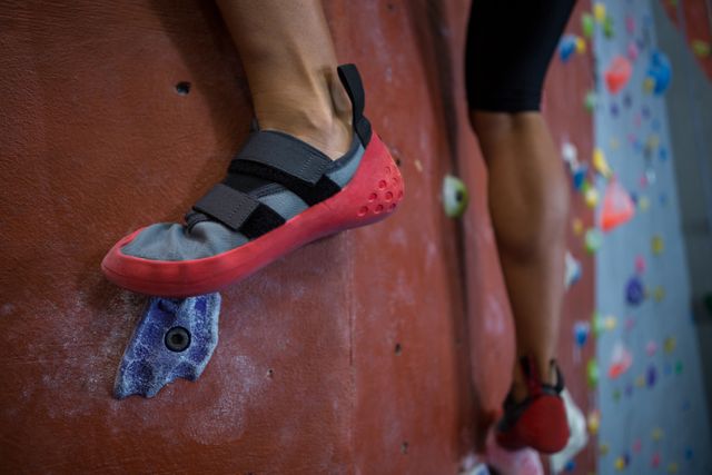 Low-section of woman practicing rock climbing in fitness studio