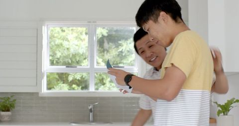 Young Men Sharing Digital Content on Smartphone in Bright Kitchen