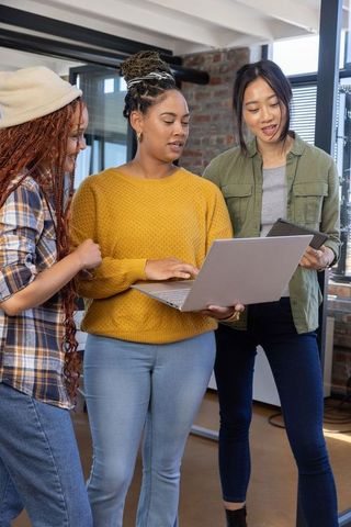 Diverse Coworkers Collaborating with Laptop and Tablet in Modern Office