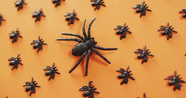 Close up view of multiple spider toys against orange background. halloween festivity and celebration concept