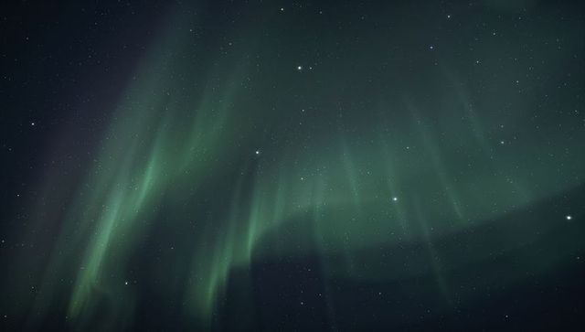 Glowing green aurora curtains sweeping across polar night sky with starry cosmic expanse