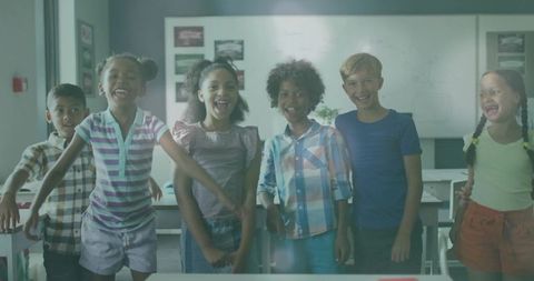 Diverse group of happy schoolchildren in classroom celebrating teamwork
