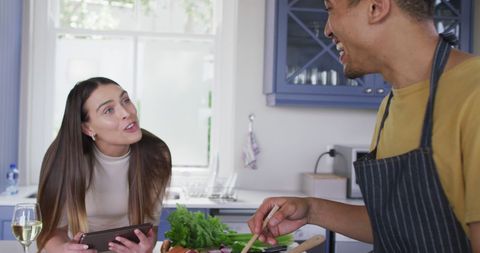 Couple enjoying cooking together at home laughing