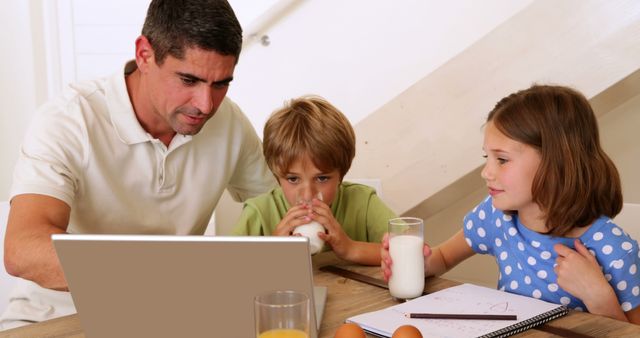 Father Using Laptop While Children Drinking Milk and Doing Homework - Download Free Stock Images Pikwizard.com