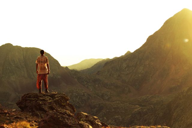 Hiking Adventure: Man Standing On Cliff At Sunset With Mountain Background - Download Free Stock Images Pikwizard.com