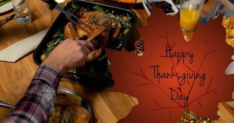 Carving roasted turkey on family wooden table with happy thanksgiving leaf graphic