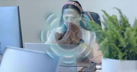 Focused Woman with Digital Interface Overlay at Office Desk