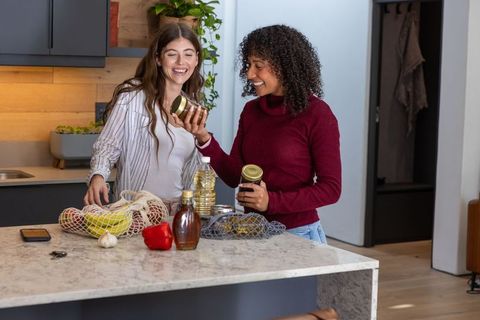 Friends unpacking groceries with mesh bags in modern kitchen