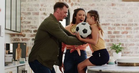 Family Celebrating with Young Girl Holding Soccer Ball and Trophy at Home