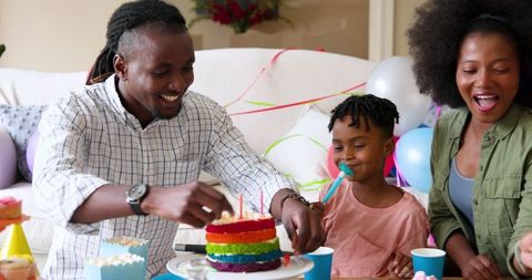 Family Celebrating Birthday with Rainbow Cake at Home