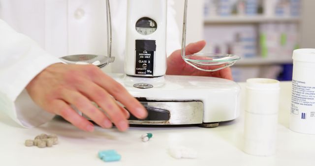 Pharmacist using a precision scale to weigh various medications in a pharmacy setting. This could be used to illustrate content related to healthcare, pharmaceutical compounding, and accurate medication dispensing. Suitable for use in medical publications, pharmaceutical brochures, and educational materials concerning pharmacy practices.