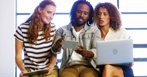 Diverse Team Engaged in Collaborative Brainstorming with Tech Devices