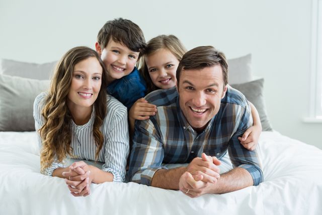 Portrait of smiling family playing on bed in bedroom at home