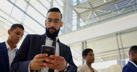 Professional Checking Smartphone in Modern Office Atrium