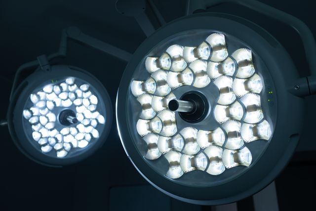 Surgical lights illuminating an operating room in a hospital. Ideal for use in healthcare articles, medical equipment catalogs, hospital brochures, and educational materials about surgery and medical procedures.