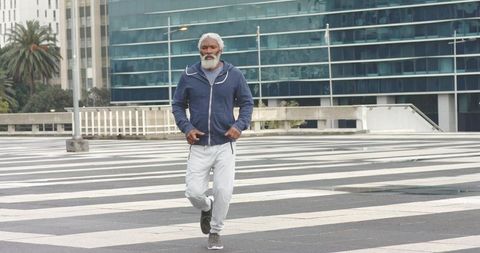 Senior African American man power walking in empty urban plaza for active aging lifestyle