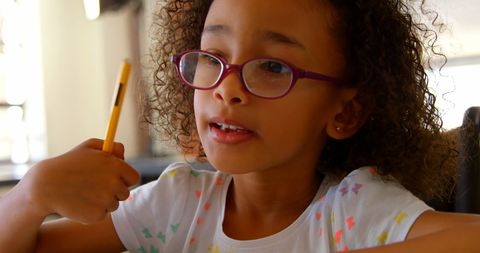 Focused young girl with glasses studying in classroom
