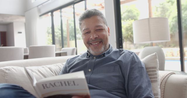 Smiling Mature Man Relaxing on Sofa with Book - Download Free Stock Images Pikwizard.com