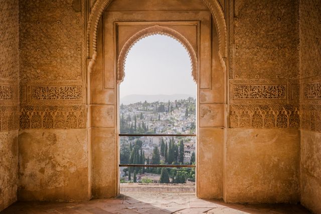 Historic Arabian arch frames panoramic cityscape, offering stunning view of urban landscape. Ideal for travel brochures, cultural heritage campaigns, or historical architecture exhibits.