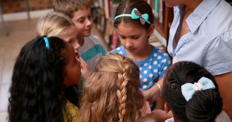 Young Students Engaging with Teacher in School Library