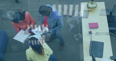 Overhead view of business team reviewing documents and tablets in modern collaborative workspace