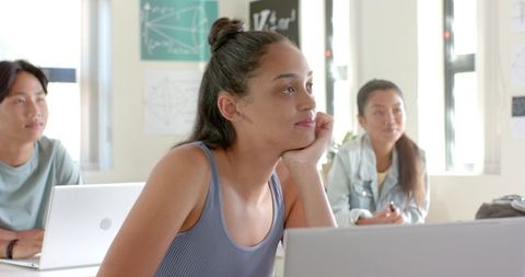 Teenage Student in Classroom Atmosphere with Laptop Appearing Distracted