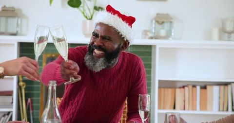 Festive Celebration: Man in Santa Hat Toasting Over Dinner
