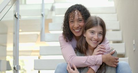 Diverse Female Friends Hugging on Modern Staircase at Home