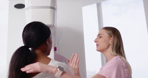 Mammography technologist positioning African American patient for breast cancer screening