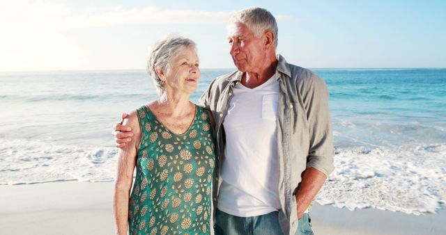 Elderly couple walking arm in arm on beach, smiling and enjoying ocean breeze. Perfect for lifestyle, senior living, retirement planning, travel, wellness, happiness, love, and relationship themes.
