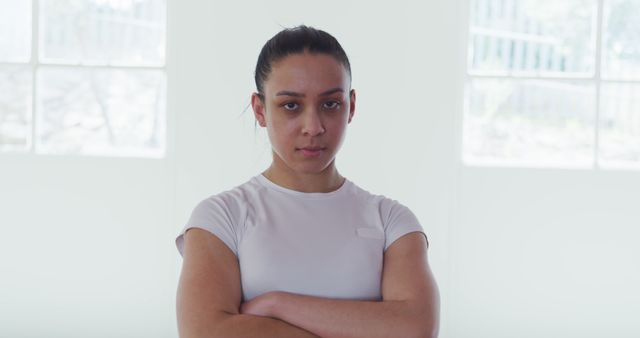 Determined Young Woman with Arms Crossed in Bright Room - Download Free Stock Images Pikwizard.com