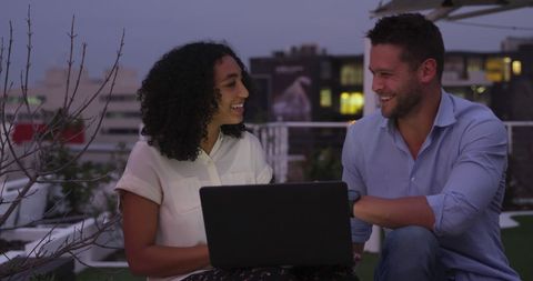 Colleagues collaborating on rooftop with cityscape view at dusk