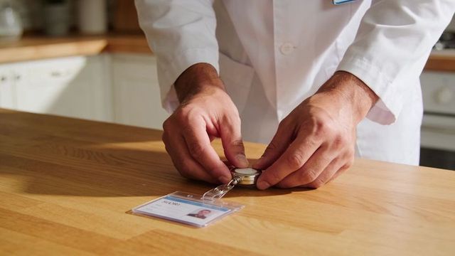 Medical professional placing retractable badge reel with id card on countertop in kitchen