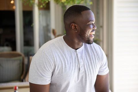 Smiling man in casual wear on patio with sunlit background