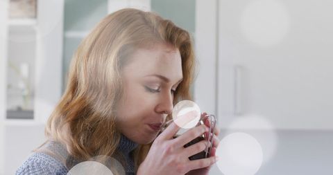 Woman enjoying hot beverage in cozy kitchen setting