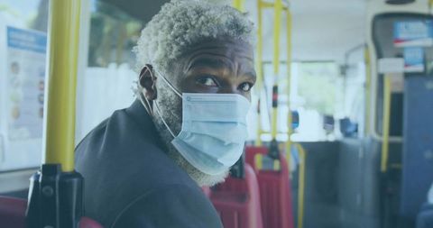 Senior man wearing mask traveling on urban bus during commute