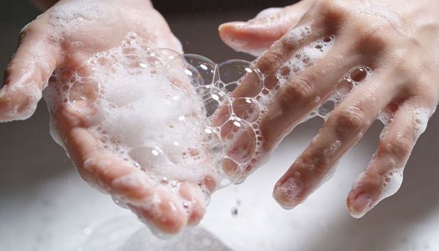 Close-up handwashing with soap bubbles, foamy lather on palms and fingers for hygiene