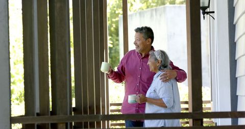 Happy Senior Couple Relaxing on Porch with Coffee and Conversation