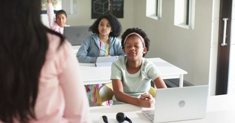 African American Teacher Leading Teen Girls in Modern Classroom With Laptops, Headphones