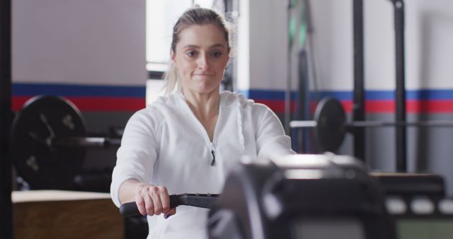 Image of determined caucasian woman using rowing machine working out at gym. Exercise, fitness and healthy lifestyle.