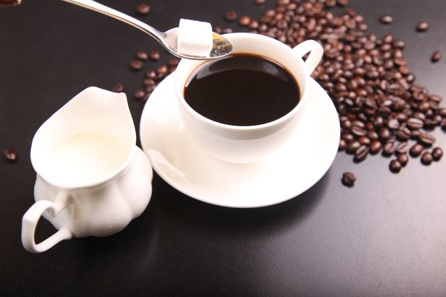 Adding Sugar Cube to Black Coffee with Creamer on Black Background  - Download Free Stock Photos Pikwizard.com
