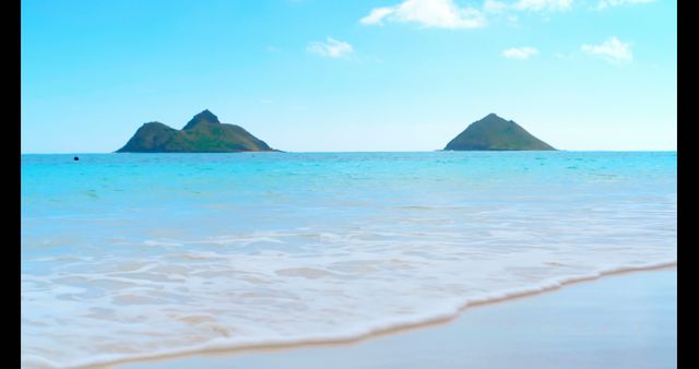 A serene beach view showcases twin islands on the horizon - Download Free Stock Photos Pikwizard.com