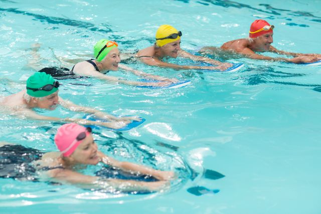 Group of senior swimmers using kickboards in a swimming pool, engaging in water exercise and fitness training. Ideal for illustrating active senior lifestyles, aquatic exercise programs, and group fitness activities. Suitable for health and wellness promotions, senior fitness classes, and community recreation programs.