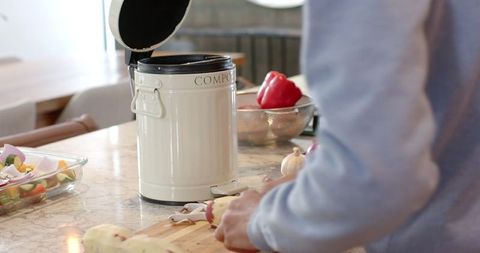 Man Preparing Meal with Eco-Friendly Compost Bin on Marble Countertop