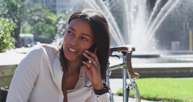 Young Woman Talking on Phone near Fountain on Sunny Day - Download Free Stock Images Pikwizard.com