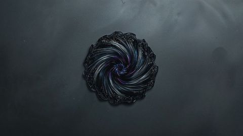 Glossy black vortex with purple highlights on dark surface