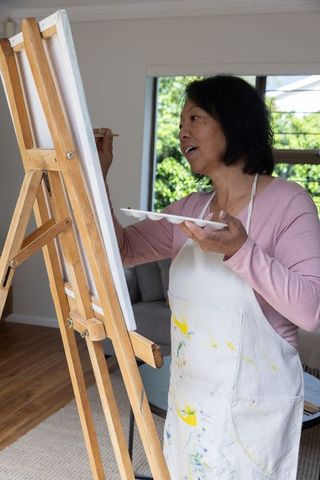 Senior Woman Joyfully Painting at Home with Canvas and Easel