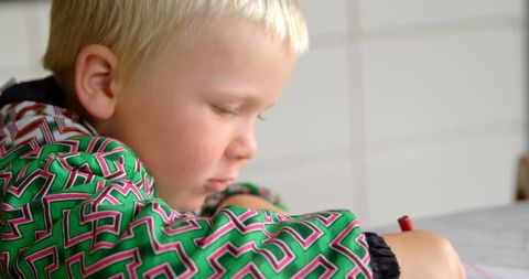 Young boy drawing with crayon at home