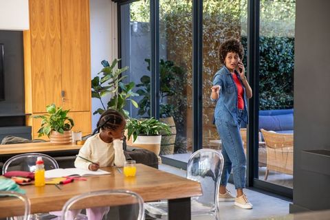 Mother multitasking with daughter doing homework at modern urban home